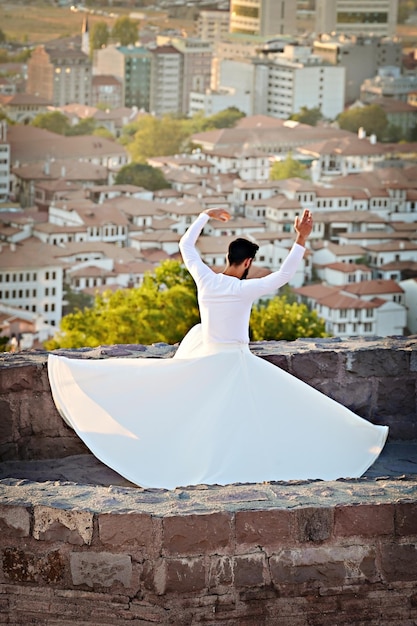 Sufi-Tanz bei Sonnenuntergang. Türkischer Mann, der Sufi-Tanz an der Wand der Burg von Ankara, Türkei, aufführt