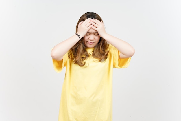Foto sufrimiento de dolor de cabeza de hermosa mujer asiática vistiendo camiseta amarilla aislado sobre fondo blanco.