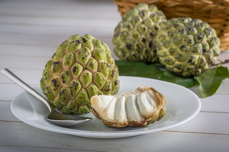 Foto sugar apple em um prato branco com colher de aço inoxidável pronta para ser consumida além de outro açúcar