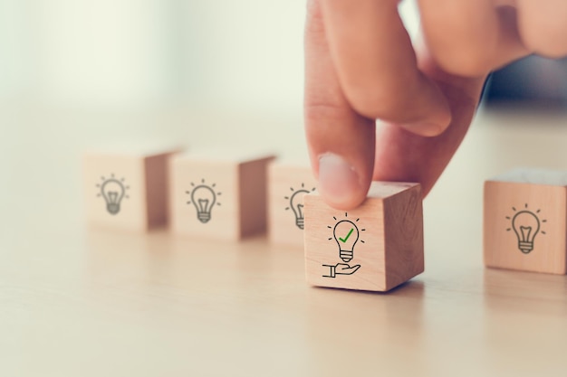 Sugestão e conceito de consultoria Nova solução de ideia Colocar cubos de madeira com lâmpada na mão ícone em belo fundo cinza e espaço de cópia Sugestão de estratégia de revisão de negócios para empresas