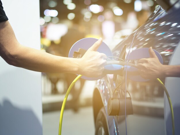 Sujete con la mano y el pulgar hacia arriba el enchufe del vehículo de carga eléctrica y el destello de luz para recargar la batería del automóvil