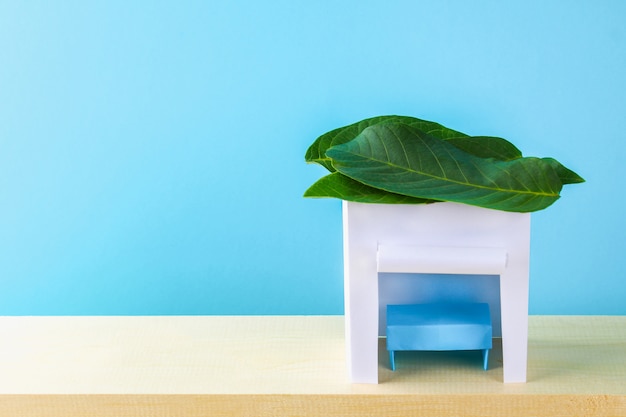 Sukkot feliz. uma cabana feita de papel coberto com folhas em um fundo azul. copie o espaço.