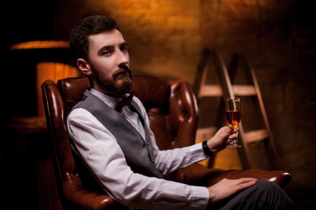 Un sumiller barbudo prueba el vino blanco en una copa. Close-up retrato de sommelier profesional.