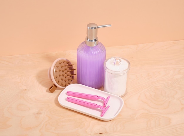 Suministros de higiene jabón líquido púrpura afeitadoras rosas almohadillas de algodón y un pincel de masaje