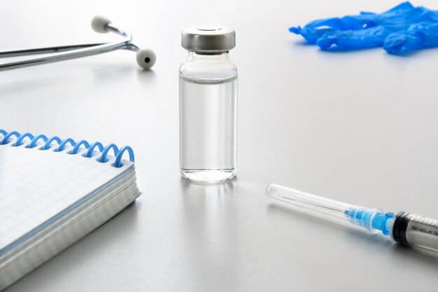 Suministros médicos, un cuaderno y un lápiz sobre la mesa blanca Vacunación