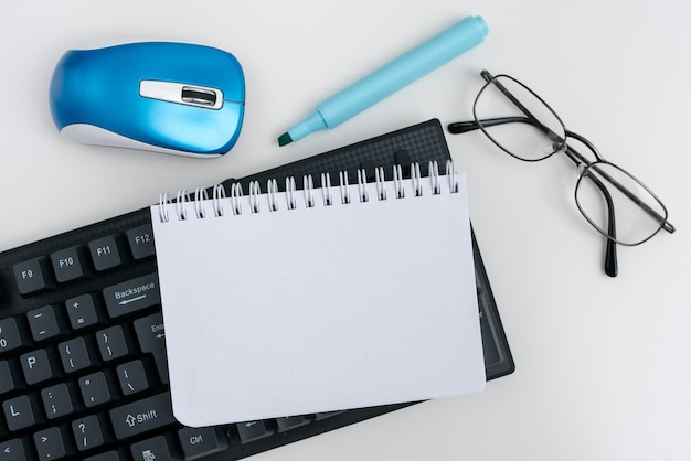 Suministros de oficina sobre escritorio con teclado y anteojos y taza de café para trabajar de forma remota Utilidades escolares variadas para estudiar con bebida caliente y anteojos