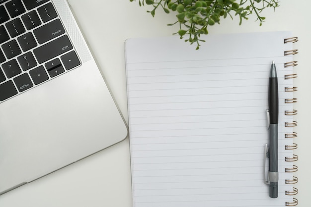 Suministros de oficina sobre escritorio con teclado y vasos y taza de café para trabajar de forma remota