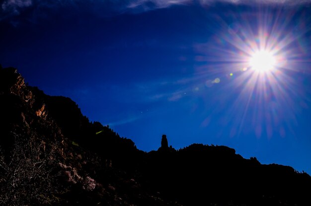 Foto sun star en un cielo azul sobre una silueta de montaña