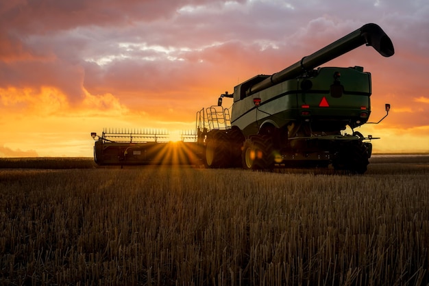 Foto sunburst através de uma colheitadeira ao pôr do sol nas pradarias em saskatchewan, canadá