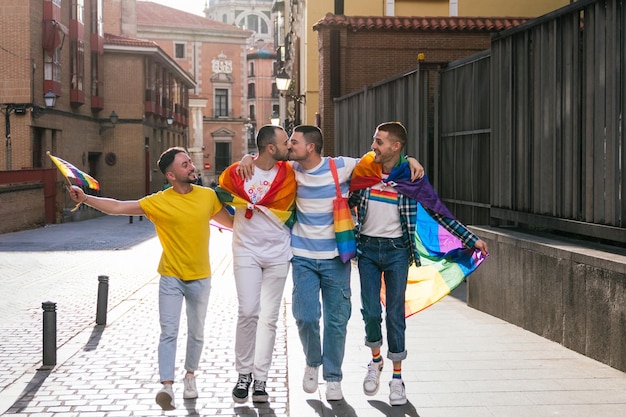 Sunny Street Serenade Alegres amigos gays se abrazan adornados con orgullo LGBT en medio del resplandor del atardecer Dos comparten un beso