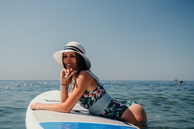 Sup stand up paddle board jovem navegando em um lindo mar calmo com águas cristalinas.