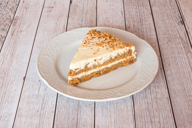 Súper y generosa porción de pastel de zanahoria con dos capas de bizcocho con frutos secos y nueces en un plato blanco