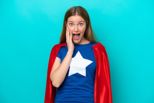 Super Hero kaukasische Frau isoliert auf blauem Hintergrund mit Überraschung und schockiertem Gesichtsausdruck