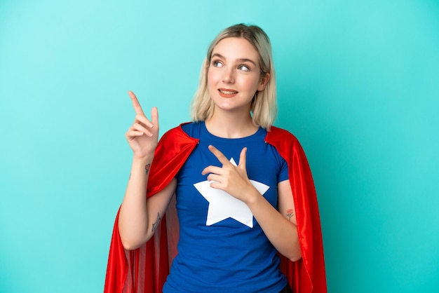 Super Hero kaukasische Frau isoliert auf blauem Hintergrund zeigt mit dem Zeigefinger eine großartige Idee