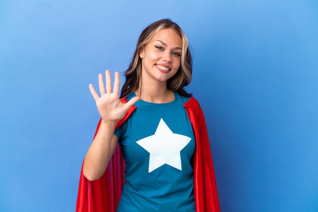 Super Hero Teenager Mädchen auf blauem Hintergrund isoliert fünf mit den Fingern zählen