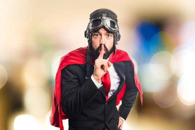 Super héroe hombre de negocios haciendo gesto de silencio sobre fondo desenfocado