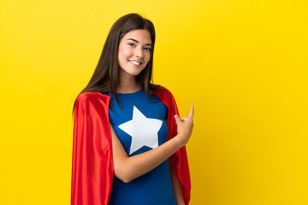 Super héroe mujer brasileña aislada sobre fondo amarillo apuntando hacia atrás