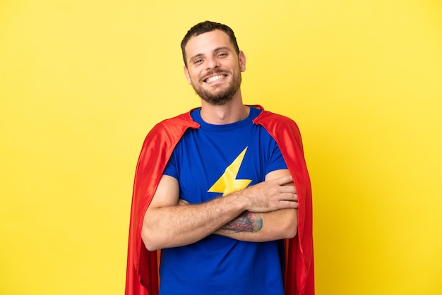 Super herói brasileiro homem isolado em fundo amarelo mantendo os braços cruzados na posição frontal