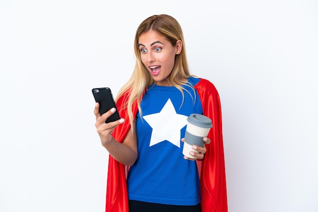 Super-herói mulher caucasiana isolada com fundo segurando café para levar e um celular