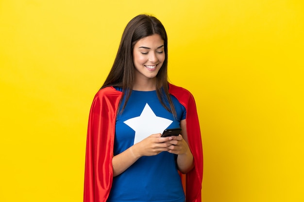 Super-heroína brasileira isolada em fundo amarelo enviando mensagem pelo celular