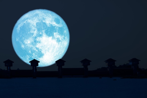 Super lua azul e barragem em silhueta no céu noturno