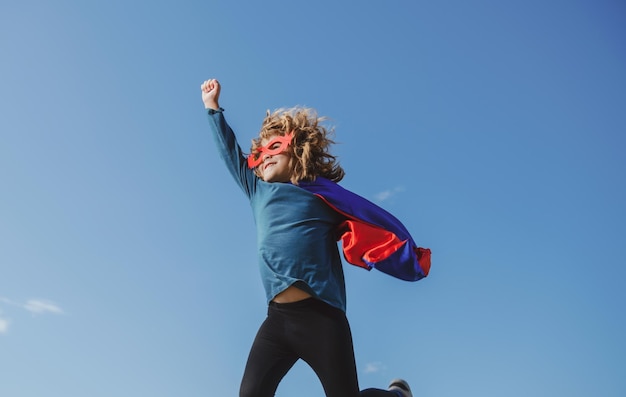 Super salto Niño con capa roja de superhéroe y máscara voladora Movimiento infantil de libertad y concepto infantil