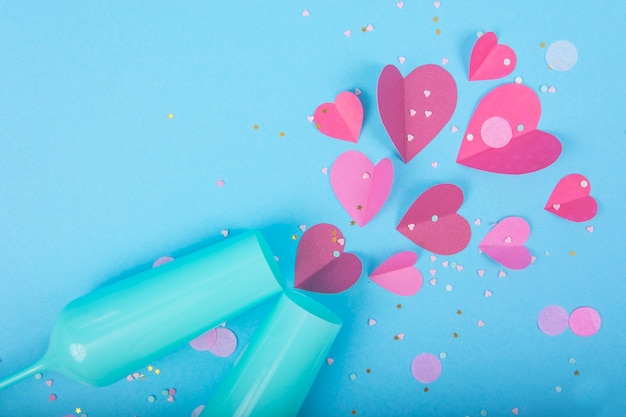 Superficie abstracta con corazones de papel, copa de champán azul para el día de San Valentín