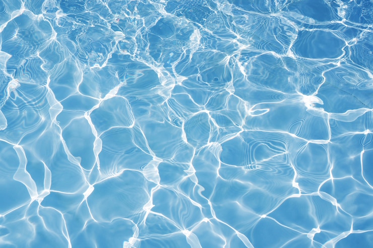 Foto superficie de agua azul con brillantes reflejos de luz solar, agua en el fondo de la piscina