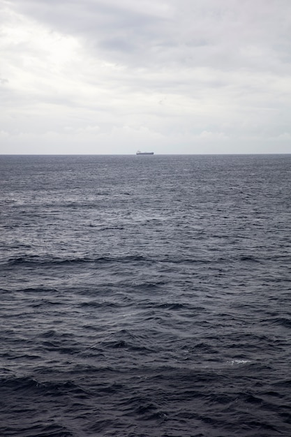 Superficie de agua azul oscuro en aguas profundas con un barco en un horizonte lejano