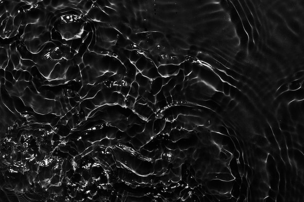 La superficie del agua es negra, el fondo es abstracto, las olas y las ondas son la textura de la crema hidratante acuática cosmética con burbujas.