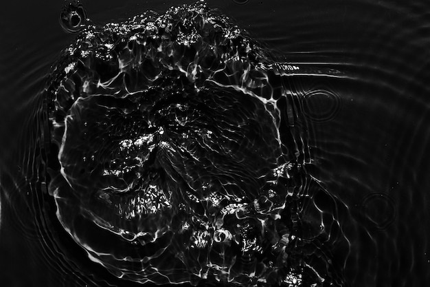 La superficie del agua es negra, el fondo es abstracto, las olas y las ondas son la textura de la crema hidratante acuática cosmética con burbujas.
