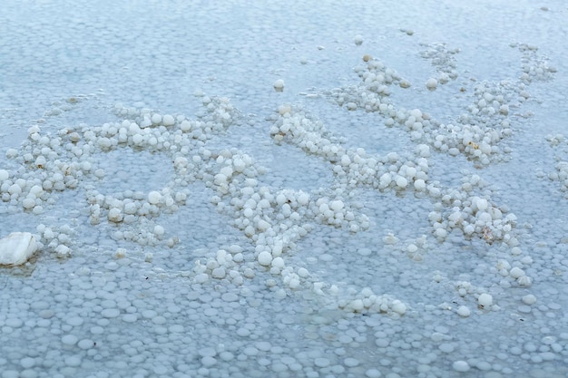 La superficie del agua de mar salada en la orilla Mar Muerto Estructura clara del fondo del Mar Muerto Las piedras están cubiertas con una costra de sal Suelo de playa salado tomado en la orilla del mar