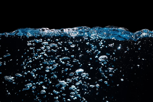 Superficie del agua con ondulación y burbujas flotando sobre fondo negro