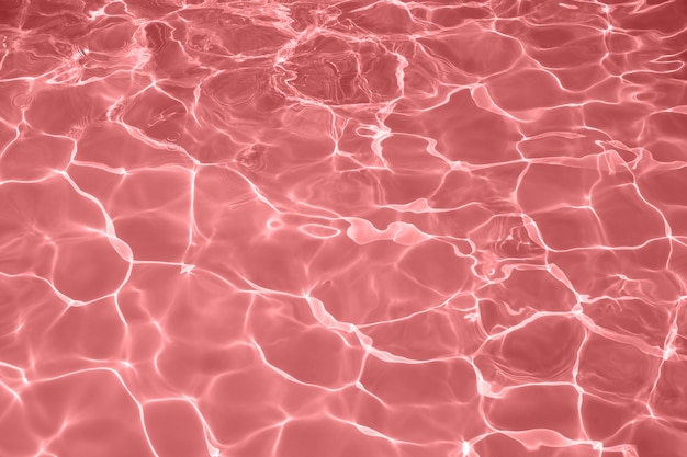 Superficie de agua roja con brillantes reflejos de luz solar, agua en el fondo de la piscina