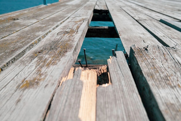 Superficie de un antiguo muelle de madera con una tabla rota y un agujero en el suelo