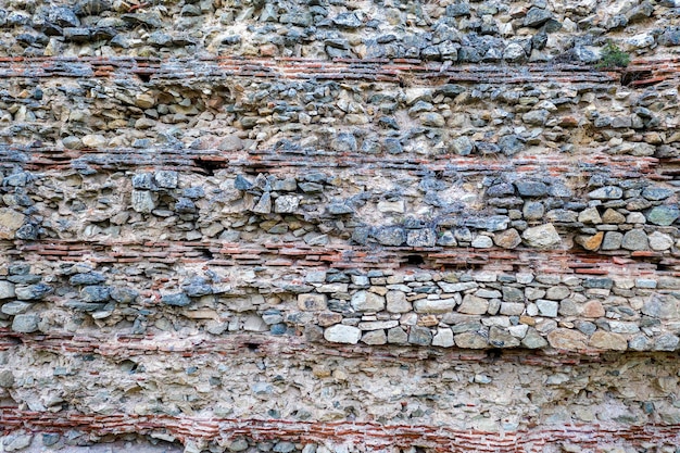 La superficie de un antiguo muro de piedra perfecto para el fondo