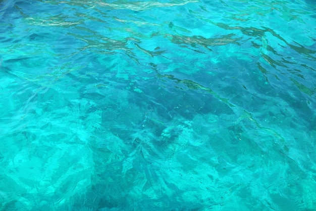 Superfície azul brilhante do oceano com ondulações e reflexo da luz do sol nas profundezas do mar