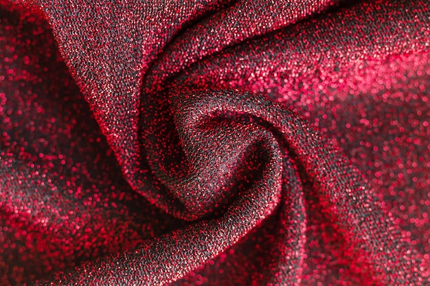 Superfície brilhante de tecido vermelho e preto com vista superior de fios de lurex