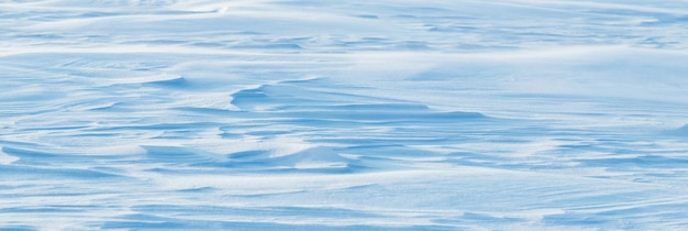 Superfície coberta de neve de fundo nevado da terra após uma nevasca de manhã à luz do sol com camadas distintas de neve