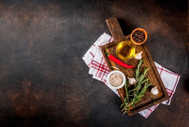 Superficie de cocción, hierbas, sal, especias, aceite de oliva en tabla de cortar