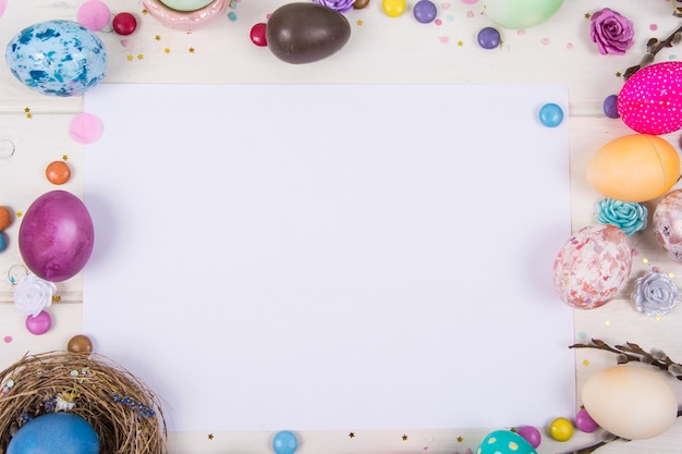 Superficie colorida con huevos de Pascua en superficie de tablero de madera blanca