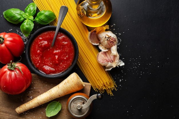 Superficie de comida italiana con espaguetis y salsa de tomate sobre fondo oscuro