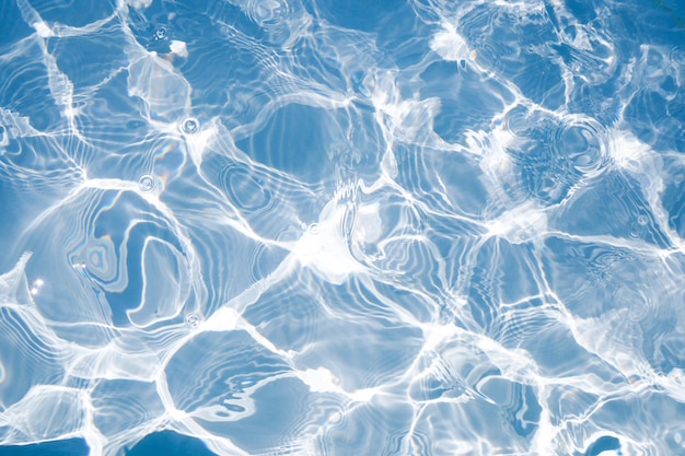 Superfície de água azul com reflexos de luz do sol brilhante, água no fundo da piscina
