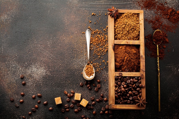 Superfície de alimentos com três tipos de café: grãos, moídos, instantâneos em caixa de madeira na velha superfície de concreto marrom. Estilo rústico. Foco seletivo. Vista do topo.