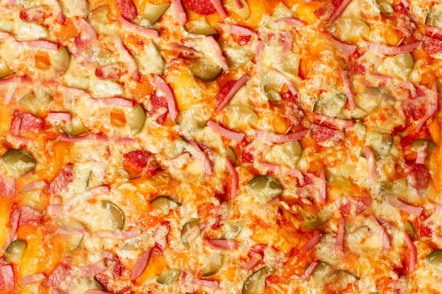 Superfície de close-up de pizza caseira assada com salame, salsicha, queijo, ervas.