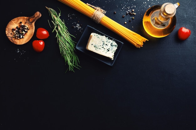 Superfície de comida italiana com vegetais, queijo e massa na superfície escura