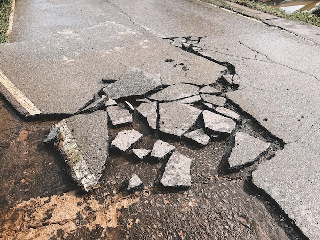 Superfície de estrada pavimentada de asfalto deteriorada com estrada danificada por descascamento à espera de estrada de reparação de estrada