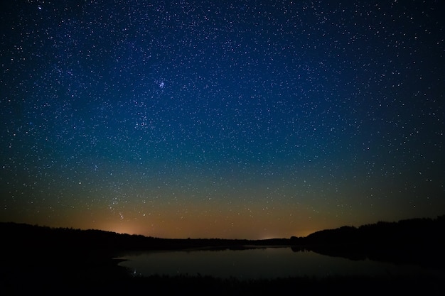 Superfície lisa do lago em um fundo do céu estrelado