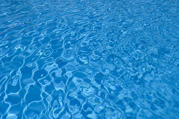 Superficie ondulada de agua azul en el fondo de la piscina
