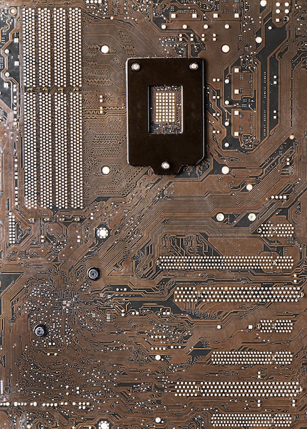 La superficie de la placa base, de color marrón oscuro, tiene un patrón de rutas de datos y la corriente tiene un punto causado por la soldadura de plomo. Es la placa de circuito debajo de la CPU.